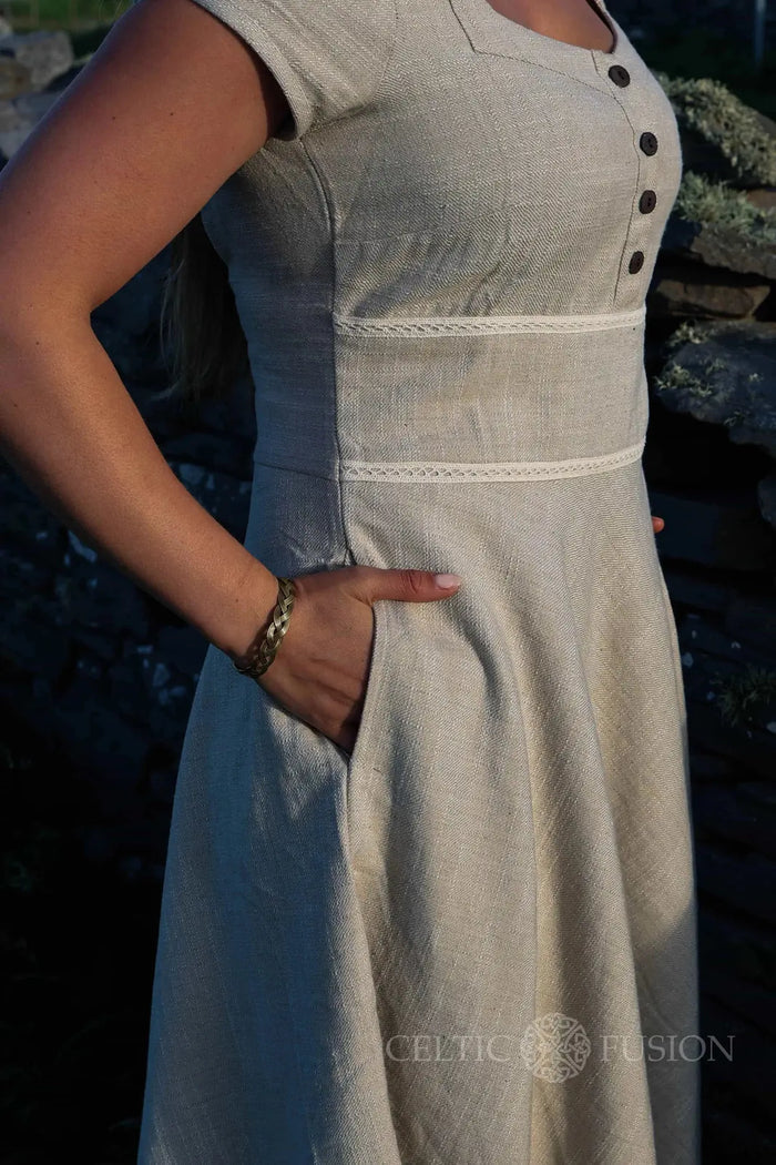 Close-up of square neck beige folklore dress showing button front bodice, fitted waist and hidden pocket detail