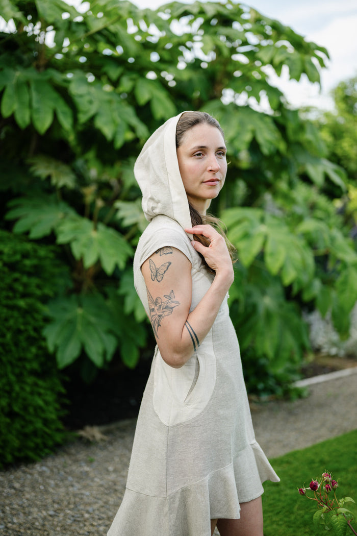 Natural cotton folklore mini dress with hood, curved side pocket and fitted silhouette.