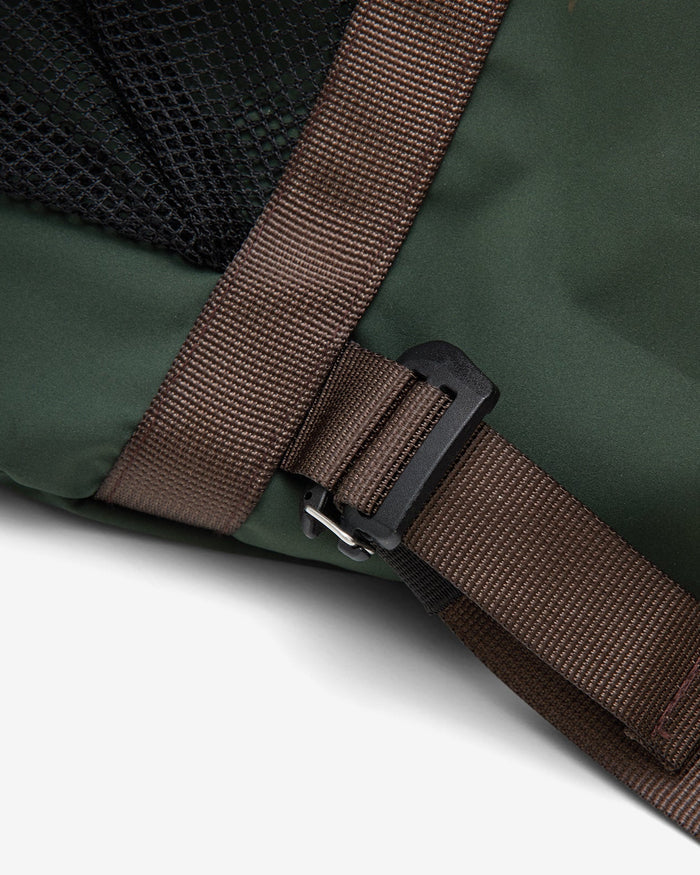 Close-up of a dark green backpack with a brown webbing strap and black plastic buckle, showing part of a black mesh pocket.