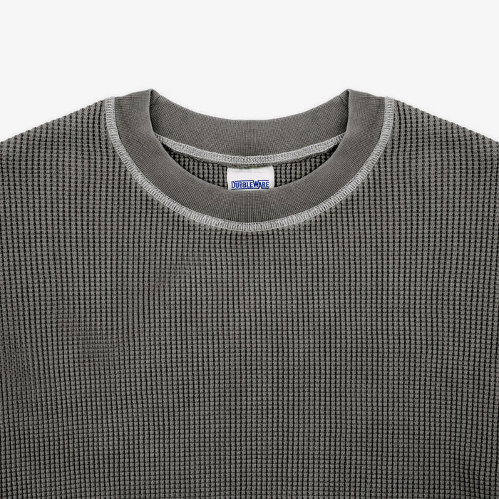 Close-up of a dark gray waffle-knit crewneck sweater with a ribbed collar and a visible Dri-Wax label inside the neckline.