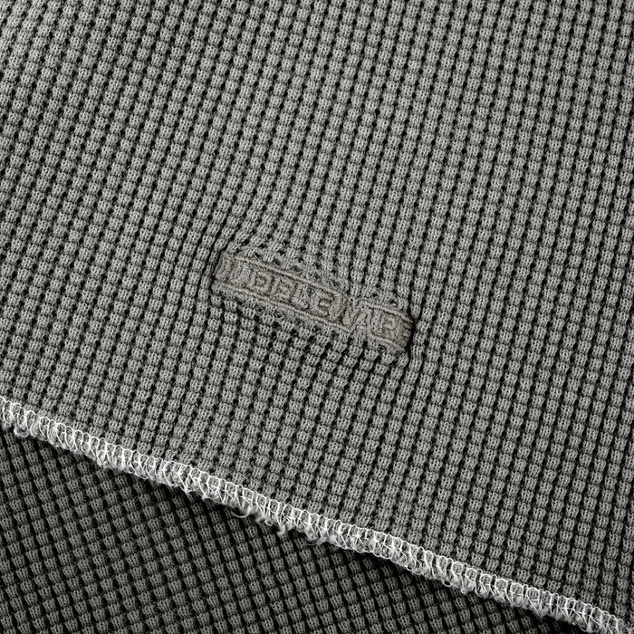 Close-up of a gray textured fabric with a visible woven brand patch reading 'BELLEWE' and a folded edge showing the material texture.
