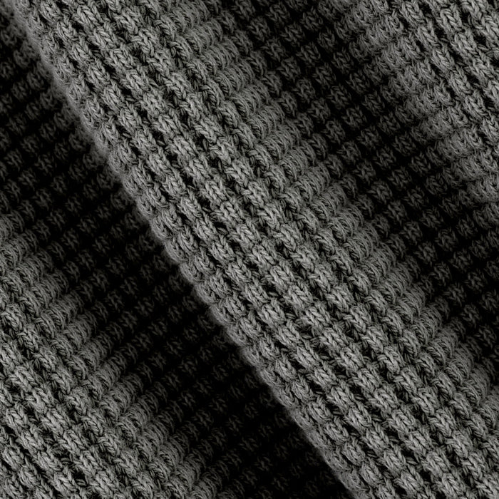 Close-up of a black and gray textured knit fabric with a diagonal shadow creating contrast.