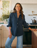 Woman standing in a kitchen wearing a navy shirt and jeans.