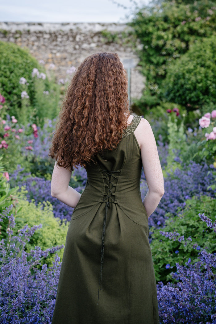 Back detail of corset back green dress with pockets, showing lace-up fit and flowing forest green skirt