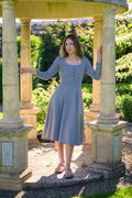 Slate blue corset midi dress with long sleeves, square neckline, button front and flowing full skirt.