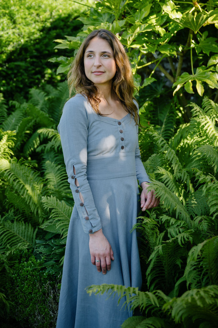 Long sleeve cotton midi dress with square neckline, fitted bodice and button details, photographed among green ferns.