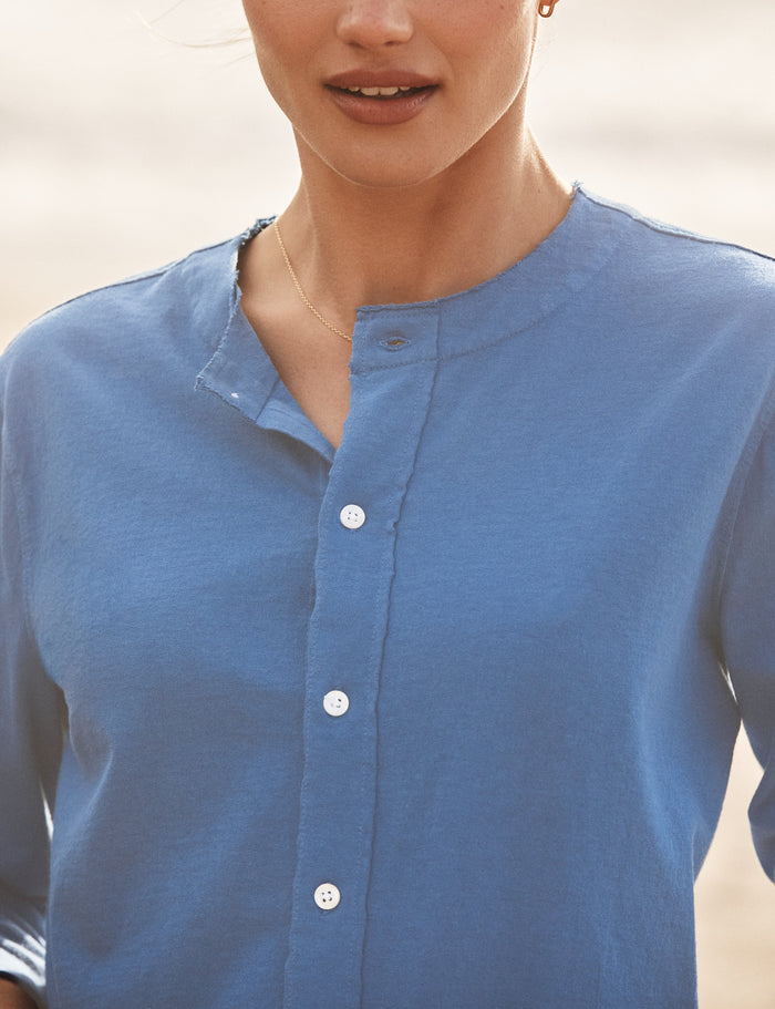 Person wearing a blue button-up shirt with a blurred background