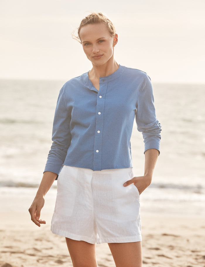 Woman wearing a blue shirt and white shorts standing on a beach.
