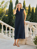 Woman in a navy dress standing on a stone pathway with greenery in the background