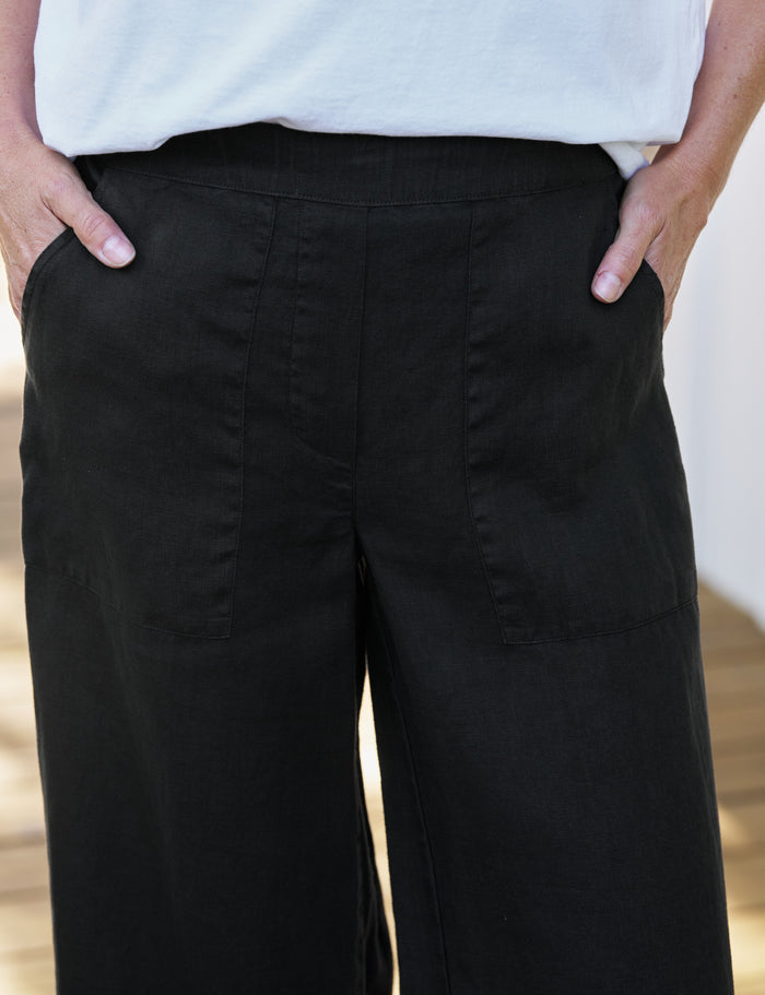 Person wearing black wide-leg pants with a white top.