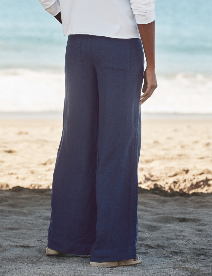 Person wearing navy pants and a white shirt on a beach