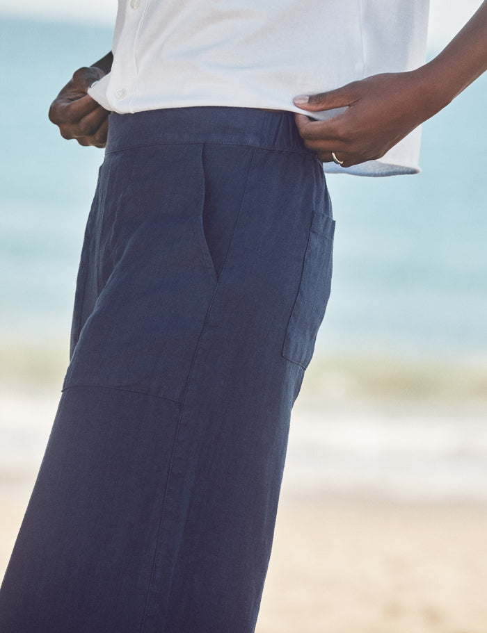 Person wearing navy pants with a blurred beach background