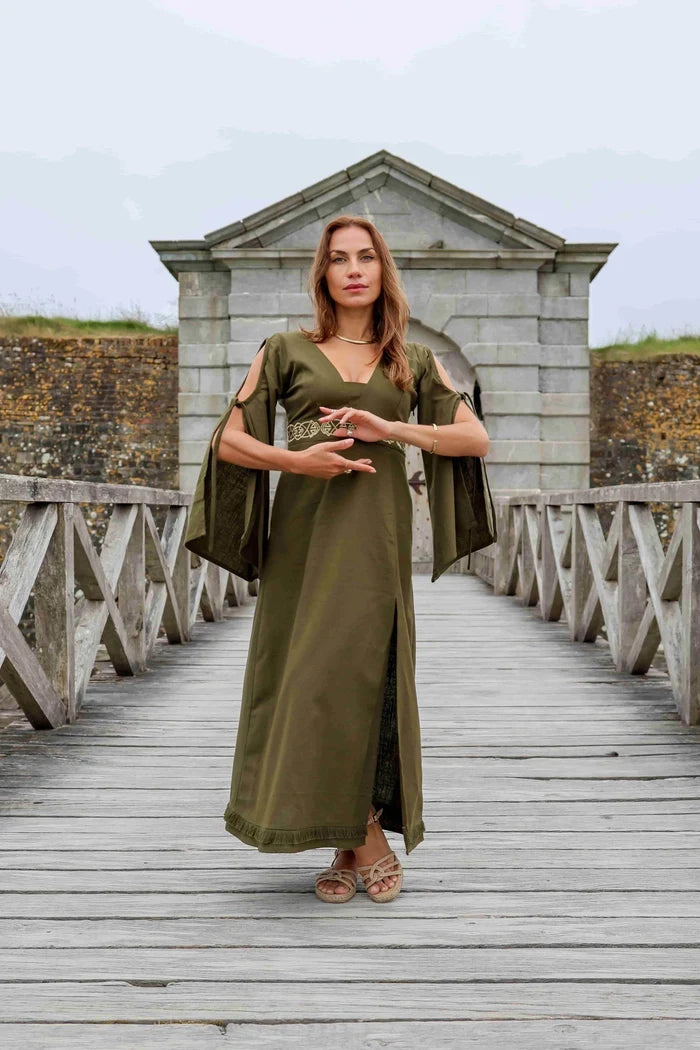 Maeve Celtic Dress worn on wooden bridge, green Celtic maxi dress with bell sleeve detail and embroidered waist for formal folklore styling.