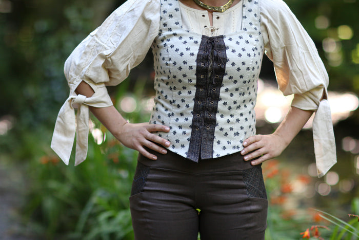 Leaf print corset top layered over a cream blouse with statement sleeves and styled with a flowing skirt.
