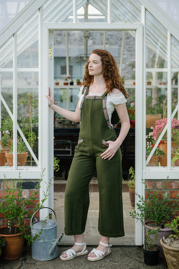Adjustable Green Dungarees styled in a greenhouse doorway with wide leg fit and checked trim details