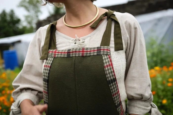 Folklore fashion garden dungarees layered over a natural blouse with tied shoulder straps and checked tweed edging