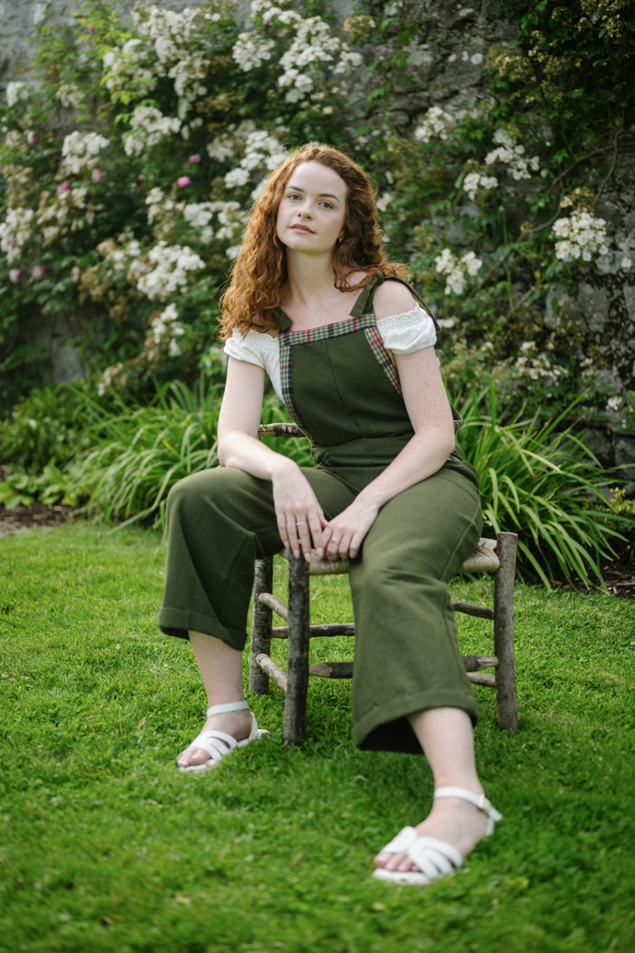 Green garden overalls with tweed details in a garden setting with wide leg silhouette and soft folk-inspired styling