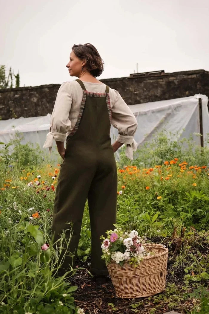 Back view of green garden overalls in the garden showing comfortable fit and cropped wide leg shape