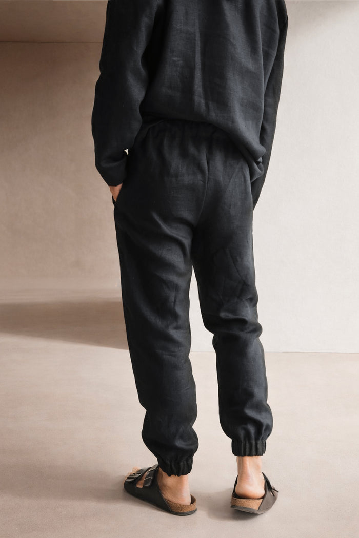 Person wearing black pants and a dark t-shirt against a neutral background