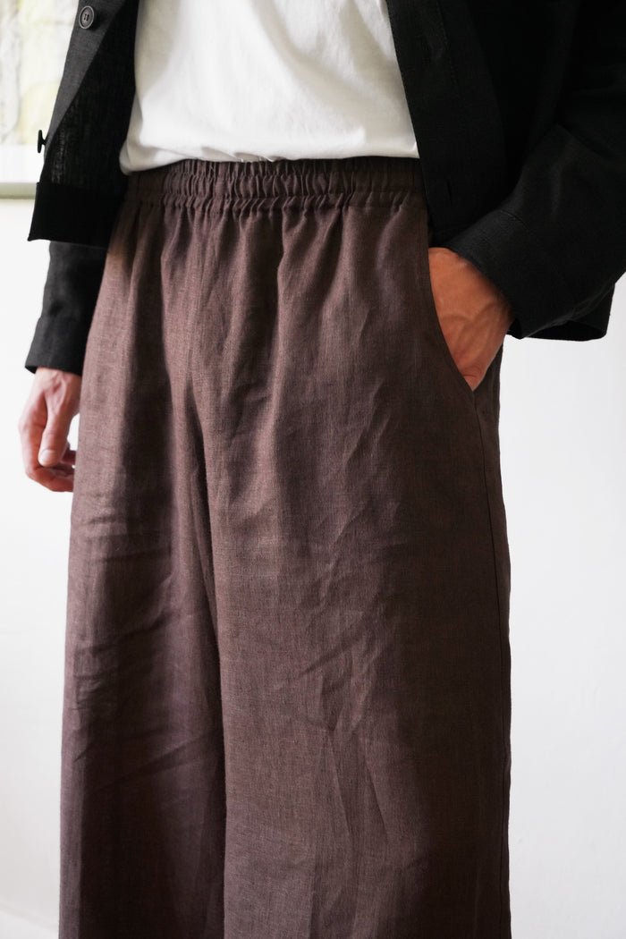 Person wearing brown wide-leg pants with a plain background