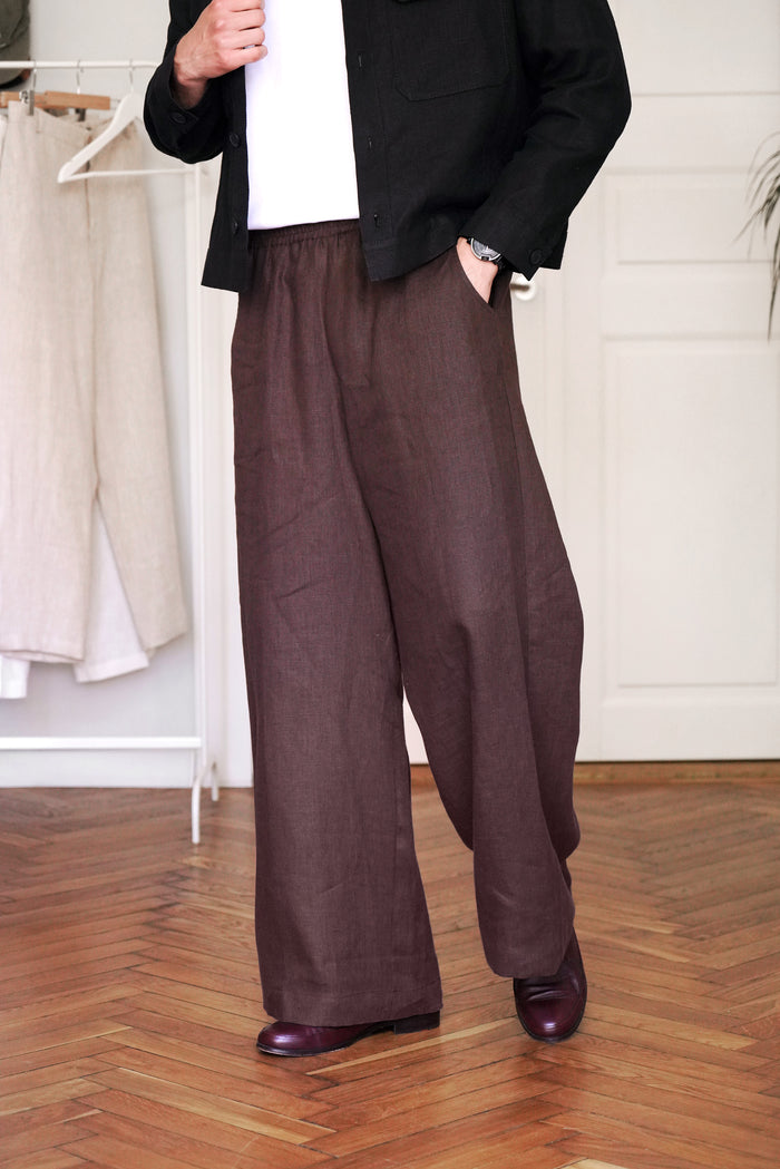 Person wearing brown wide-leg pants in a room with wooden flooring.