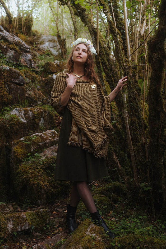 Handwoven wool blend shawl with fringe and brass oak leaf brooch, styled as a woodland shawl over a dark green folklore dress by Celtic Fusion