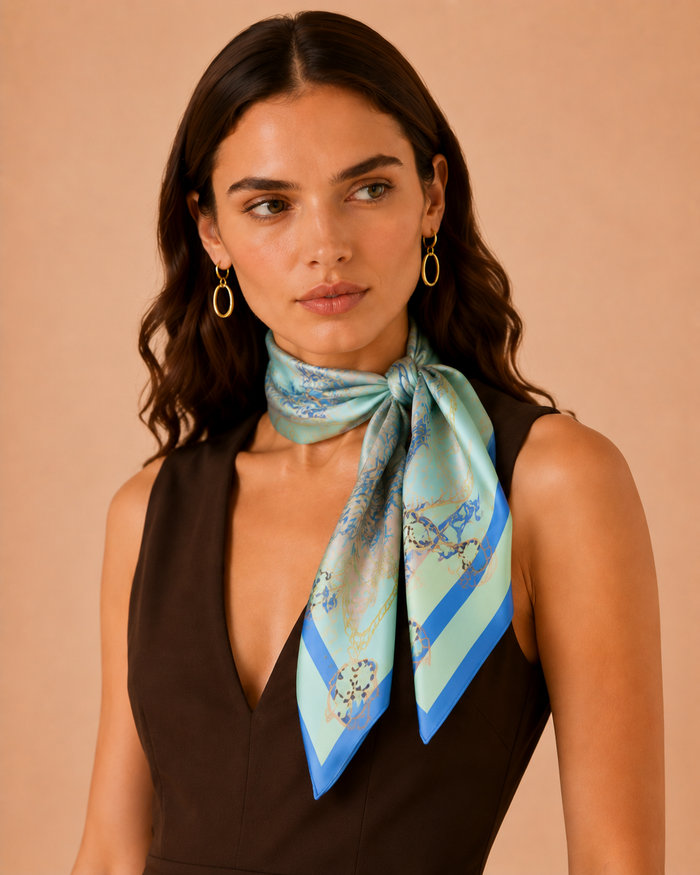 Designer silk scarf in pastel blue with delicate botanical elements, ornamental details, and a modern luxury aesthetic.