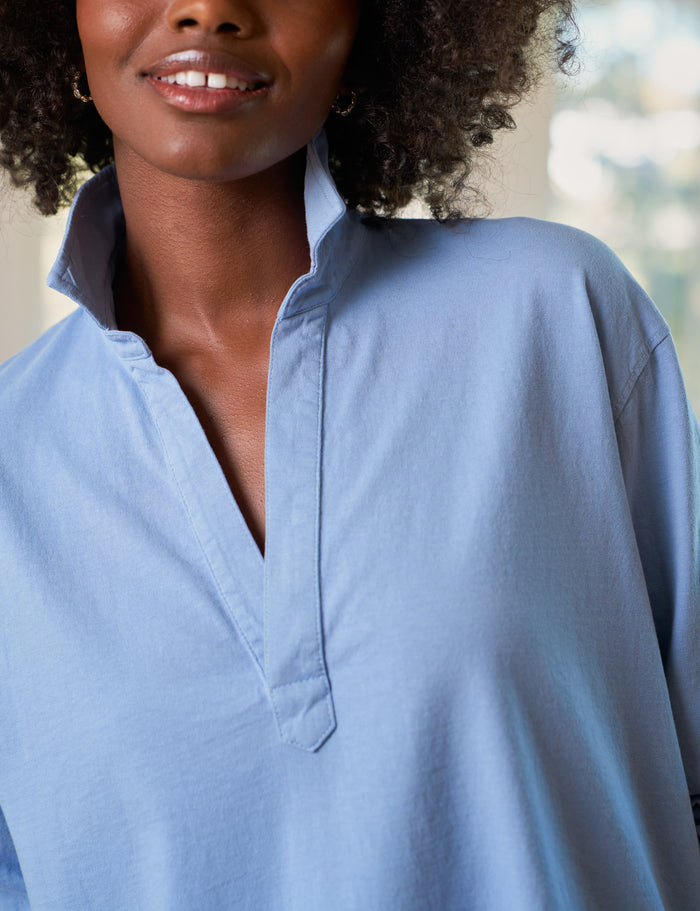 Woman wearing a light blue shirt with a blurred outdoor background