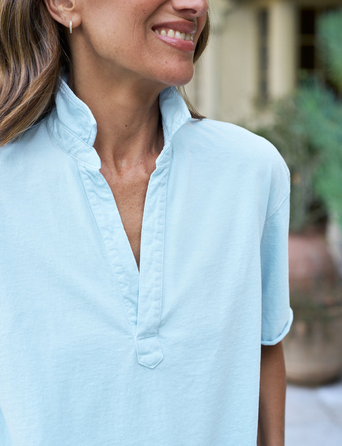 Woman wearing a light blue shirt with a blurred outdoor background