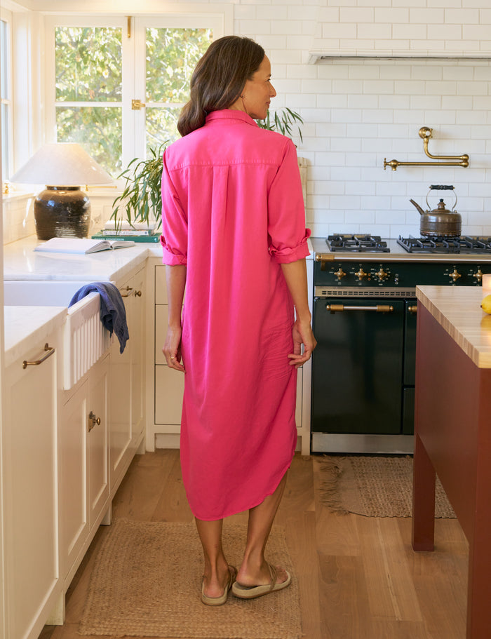 Woman in a bright pink dress standing in a kitchen.
