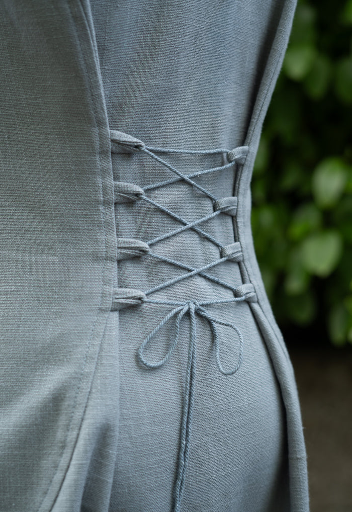 Natural cotton hooded folklore dress showing the adjustable corset lace-up back.