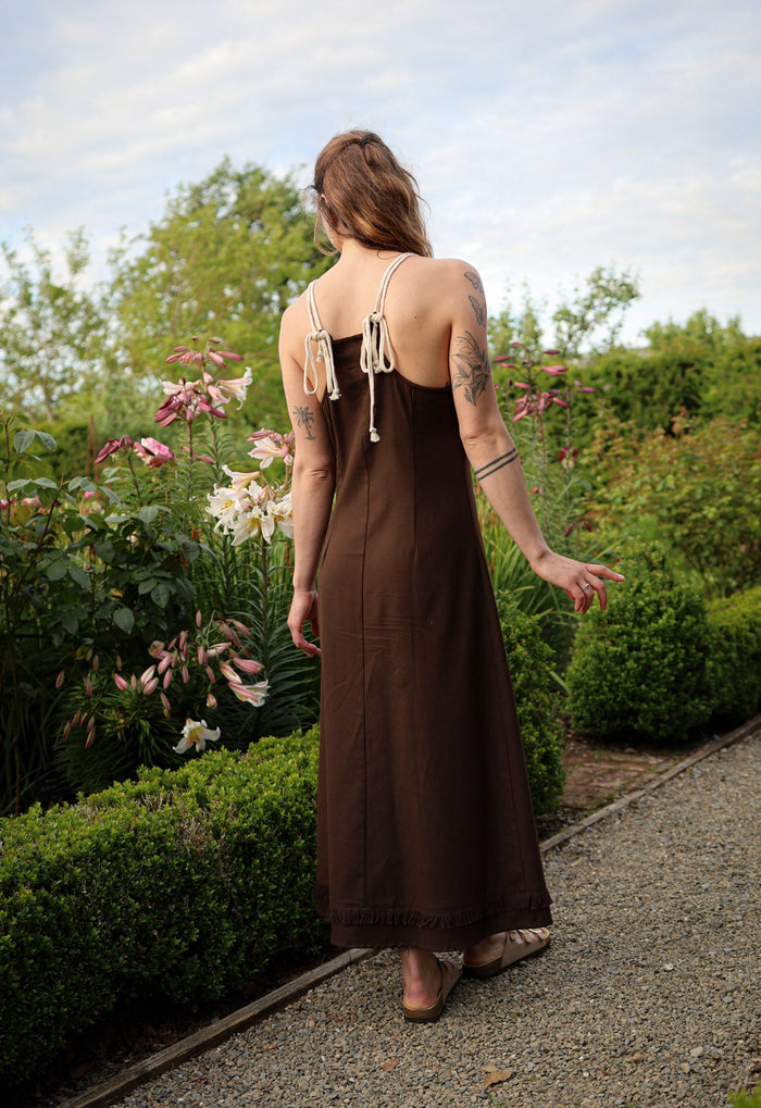 Back view of brown boho maxi dress with rope tie back and dramatic hand-plaited ties falling from the neckline