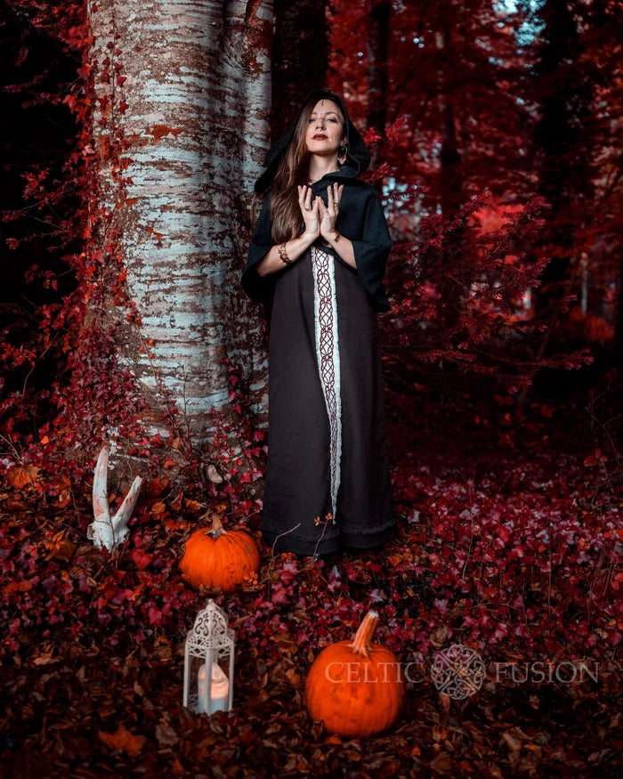 Sleeveless Brown Celtic Dress layered with a dark hooded cape in an autumn woodland folklore styling