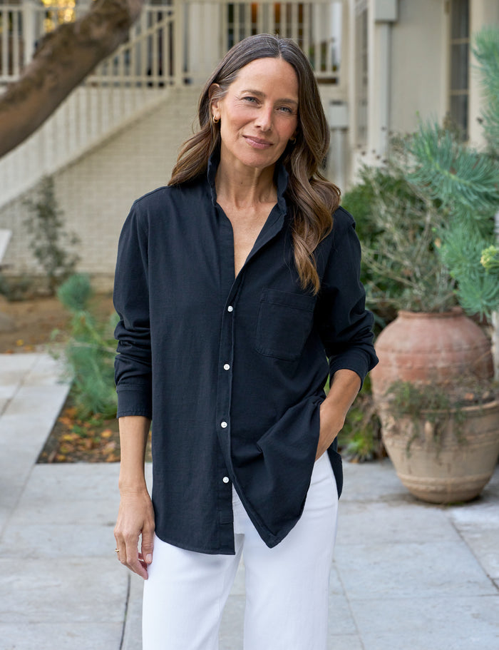 Woman wearing a navy shirt and white pants standing outdoors.