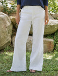 Person wearing white pants standing outdoors with rocks and greenery in the background