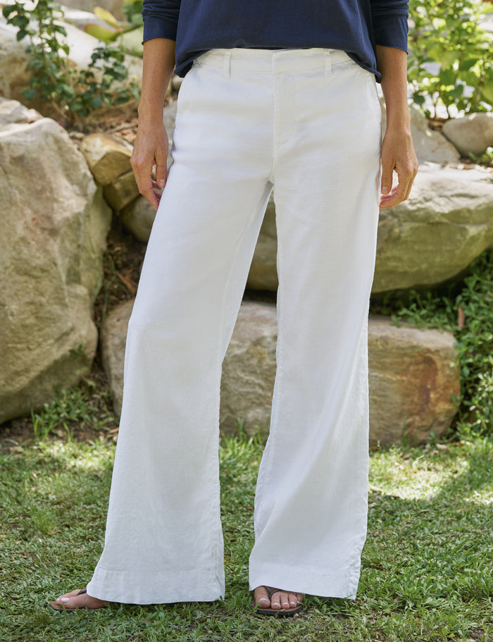 Person wearing white pants standing outdoors with rocks and greenery in the background