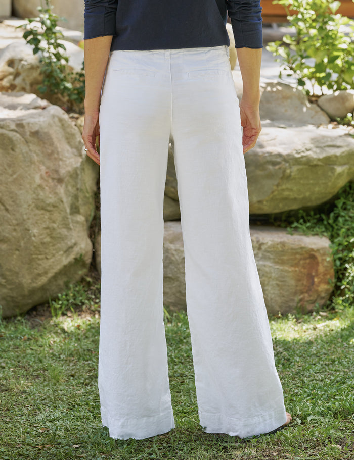 Person wearing white pants standing outdoors with rocks and greenery in the background